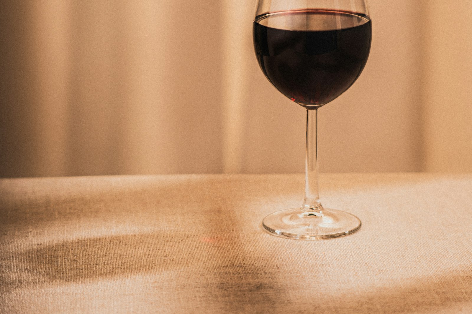A single glass of red wine on a table at home