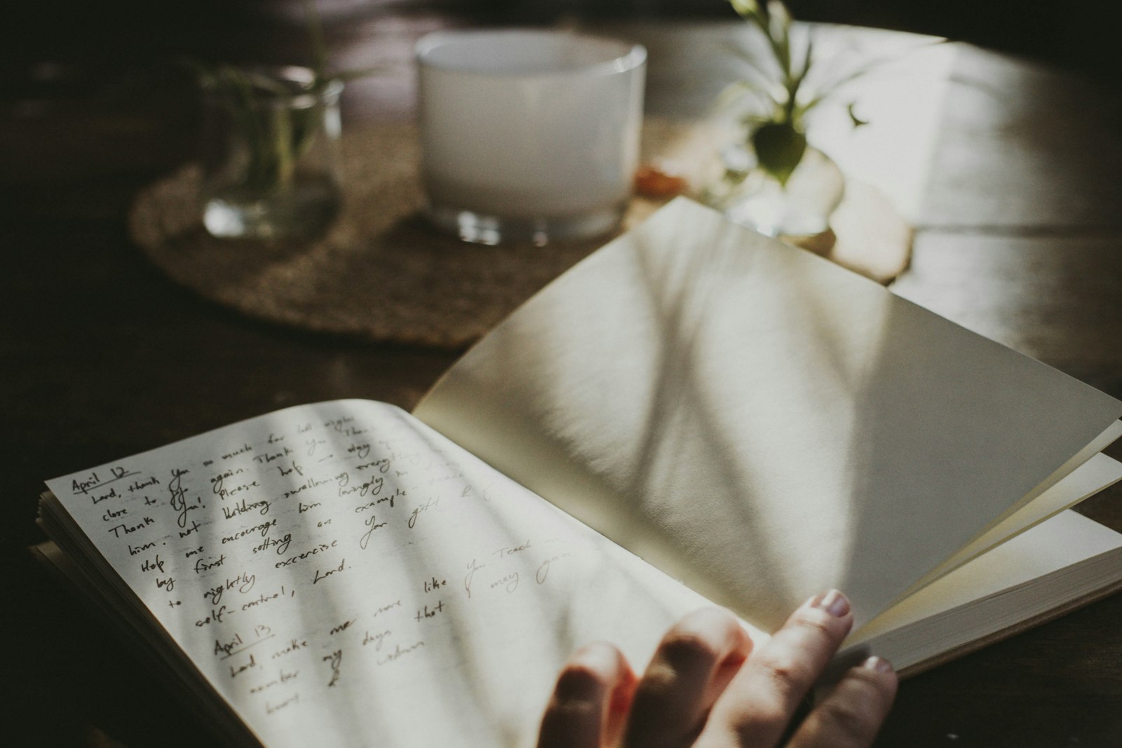 An open notebook and pen beside a cup in morning light