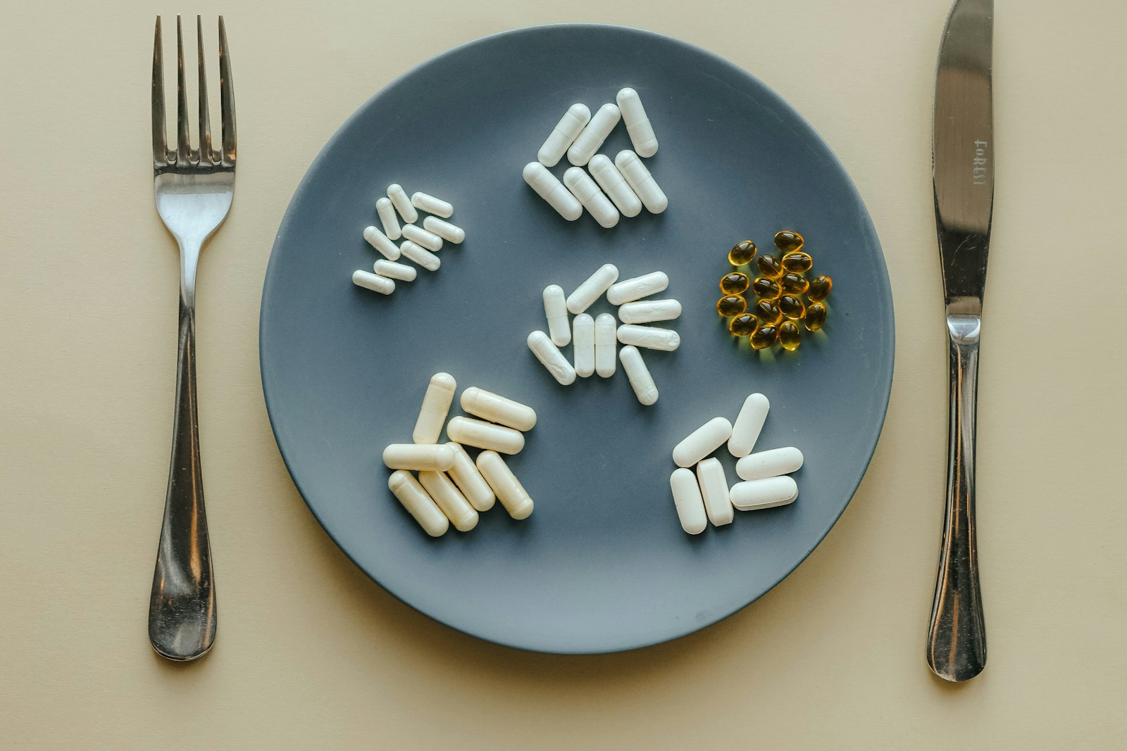 Supplement capsules arranged on a plate with cutlery