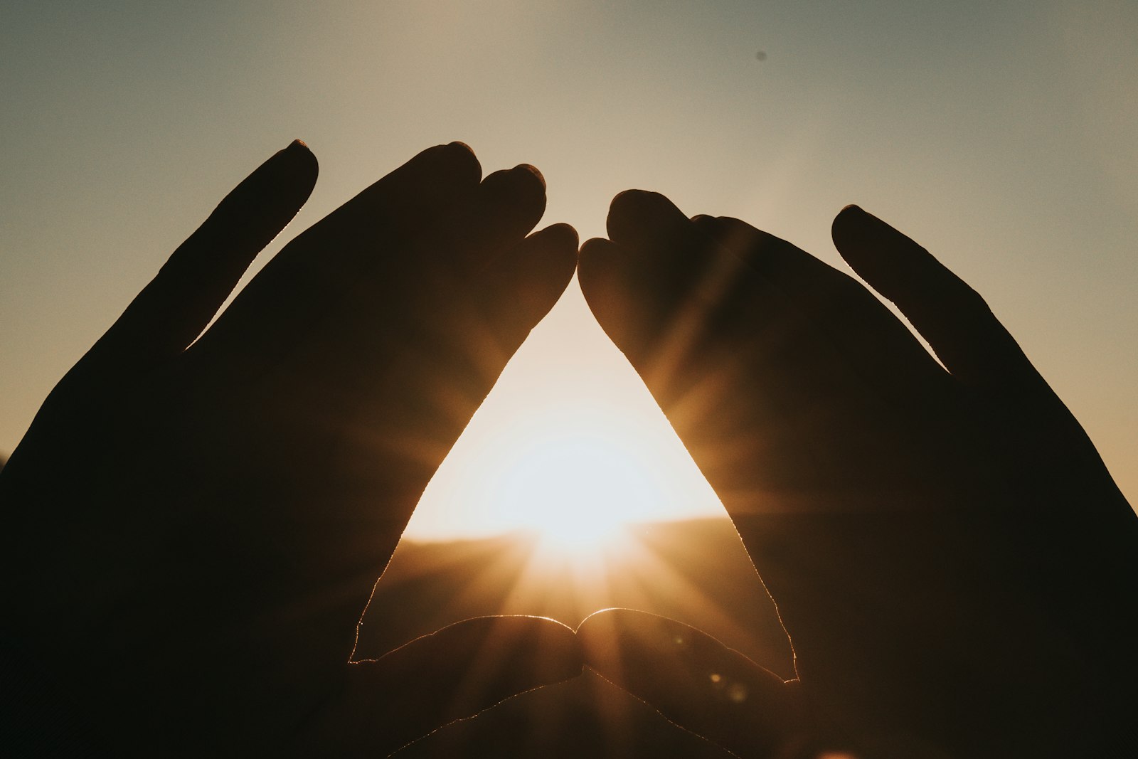 Open hands framing low evening sunlight